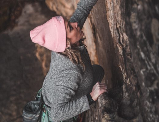 Frau klettert an einer Felswand